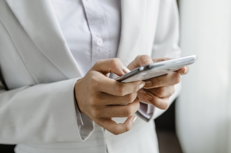 Businesswoman sending text message by mobile phoneの写真素材