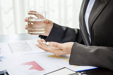 Business person holding medicine and glass of waterの写真素材