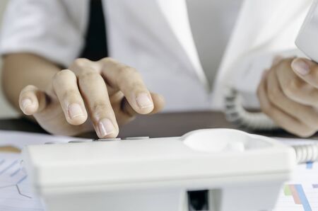 Woman dialling on a telephone in an officeの写真素材