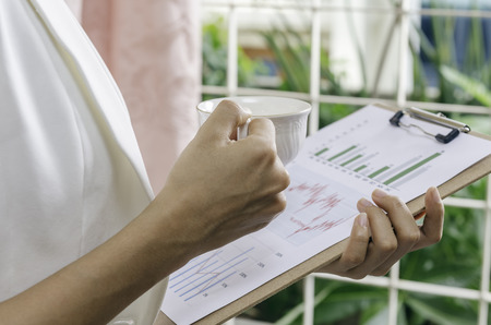 businesswoman reviewing graphs with a cup of teaの写真素材