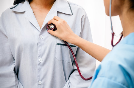doctor listening to patients heartbeat with stethoscopeの写真素材