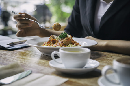 focus on woman eating spaghetti with cup of teaの写真素材