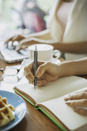 designer writing in her book in a coffee shopの写真素材