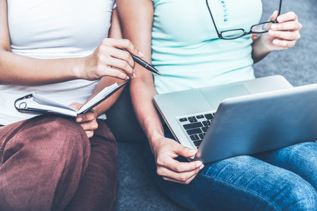 two college students pointing and discussing on their laptop