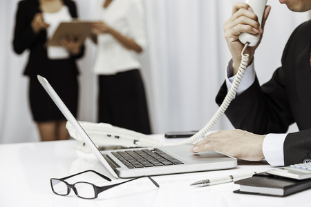 inside the executive office, the boss talking on the phone and assistants discussing workの写真素材
