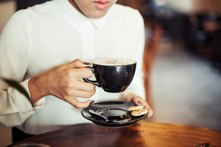 close up of a woman drinking coffee by a wooden table