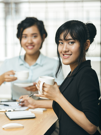 Two young women smiling with coffee in handsの写真素材