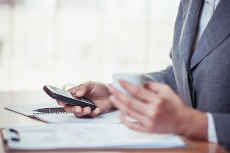 Businesswoman surf internet on smartphone and holding coffee cub
