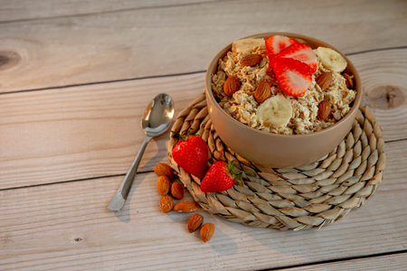 Oatmeal porridge with strawberries and nuts on light wooden backgroundの写真素材