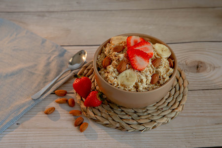 Oatmeal porridge with strawberries and nuts on light wooden backgroundの写真素材