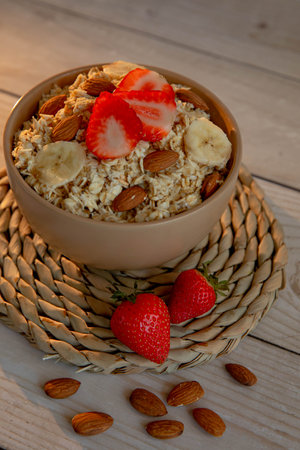Oatmeal porridge with strawberries and nuts on light wooden backgroundの写真素材