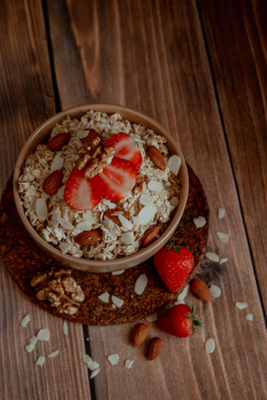 Oatmeal porridge with strawberries and nuts on dark wooden backgroundの写真素材