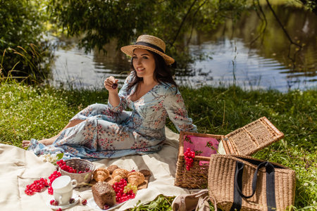 Girl in straw hat sitting on blanket in nature in summer at picnicの写真素材