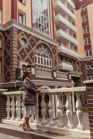 Stylish brunette on the street against the backdrop of modern buildingの写真素材