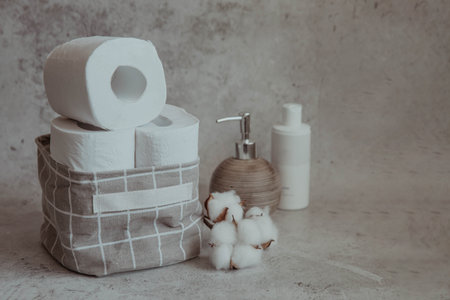 Toilet paper in a basket with cotton on a light backgroundの写真素材