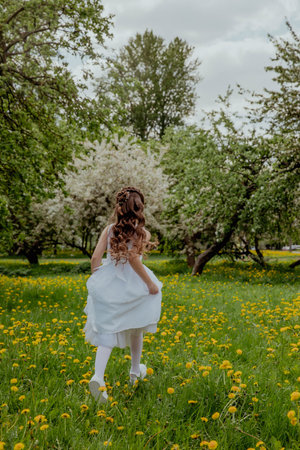 Girl in white dress running through a blossoming apple orchardの写真素材