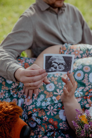 Snapshot of childs embion in hands of happy parentsの写真素材