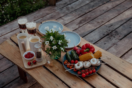 Vegetables and grilled steaks on wooden table in summer at picnicの写真素材