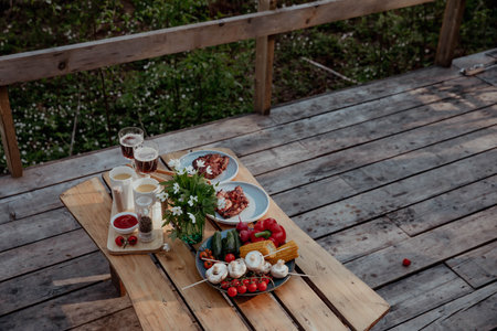 Vegetables and grilled steaks on wooden table in summer at picnicの写真素材