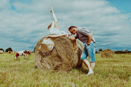Couple with haystack in village against a backdrop of cowsの写真素材