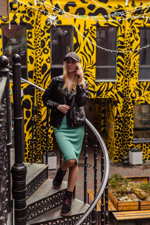 Girl in black cap and leather jacket with phoneの写真素材