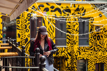 Girl with red hair in black jacket smilling on yellow backgroundの写真素材