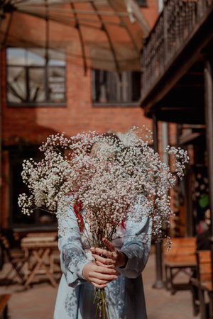 Bouquet of gypsophila flowers in hands of girl covering her face