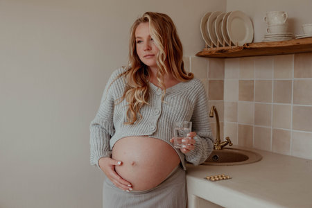 Pregnant girl with vitamins and pills and a glass of waterの写真素材