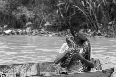 SIEM REAP, CAMBODIA-AUG 10  Poor boy on Tonle Sap displays with a snake to tourists on August 10, 2013 at Siem Reap, Cambodia のeditorial素材