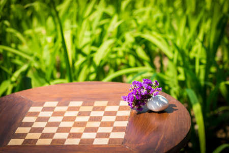 chessboard in wooden table with flower vase in gardenの写真素材