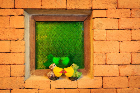 Bird statue on brick wall with green windowの写真素材