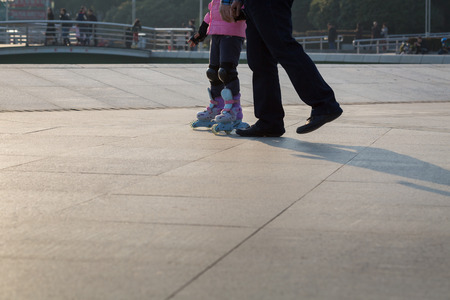 Father and daughter holding hand in hand to play roller bladeの写真素材