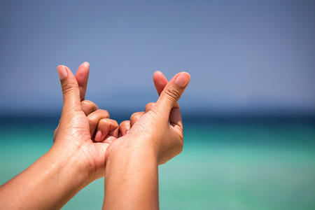 female hands in heart shape on sea beach at day time background, Summer seasonの写真素材