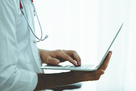 Asian doctor with laptop and stethoscope on white background, medical and technology conceptの写真素材