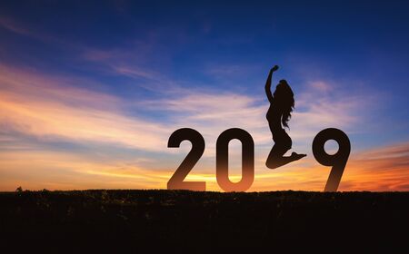 New year 2019 concept Silhouette young happy woman jumping with sky background at sunsetの写真素材