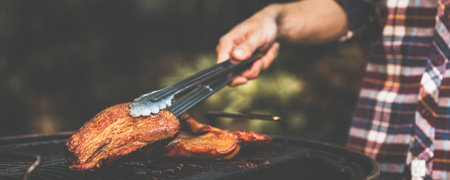 Family making barbecue of grill crispy pork in dinner party camping at nightの写真素材
