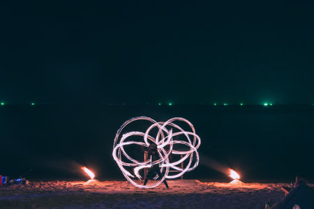 Summer Travel vacation concept, Man spinning fire steel wool with water reflection on sea in beach club party at night in Koh Samui, Thailandの写真素材