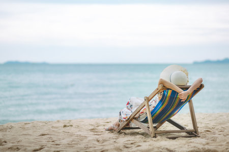 Summer beach vacation concept, Travel asian woman with hat and dress relax on chair beach at Pattaya, Chon Buri, Thailandの写真素材