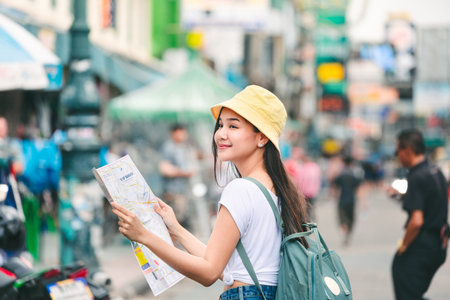 Travel vacation city concept, Young happy traveler asian woman with map and backpack walking on Khaosan Road outdoor market in Bangkok, Thailandの写真素材