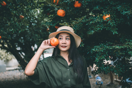 Portrait of Happy traveler asian woman with orange holding hand relax in orchard and cafe at Thailandの写真素材