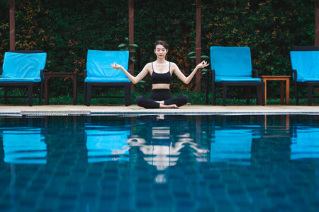 Fitness asian woman doing yoga meditation for relax and healthy beside swimming pool background, Outdoor sport and healthy conceptの写真素材