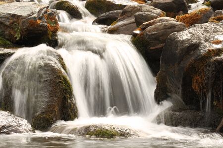 blurred water cascade with moss covered stonesの写真素材