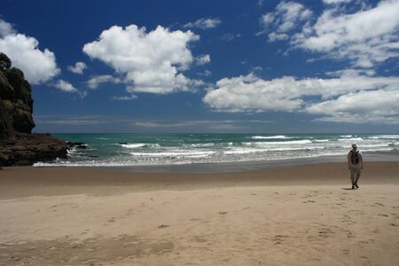 man walking across Piha Beach in New Zealandの写真素材