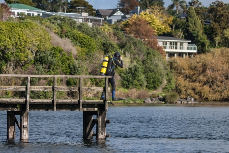 scuba diver jumping off wooden jettyの写真素材