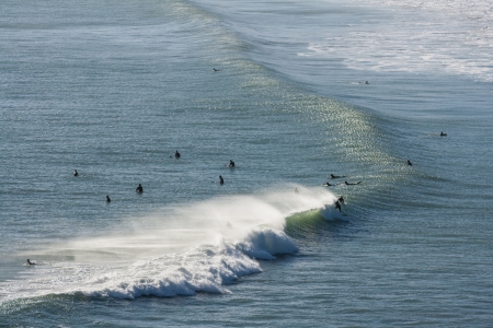 surfers riding on wave at Piha beachの写真素材