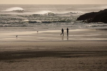 people on beach watching tidal wavesの写真素材
