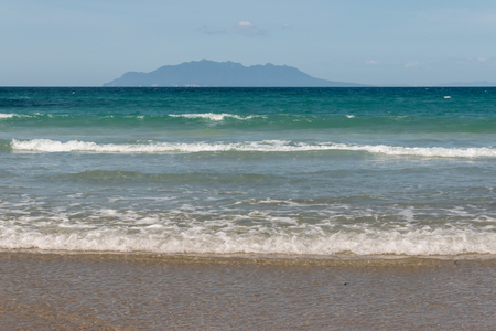 tidal waves with silhouette of island on horizonの写真素材