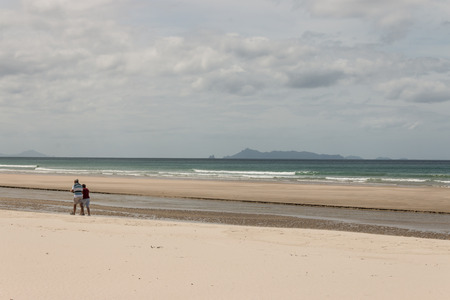 retired couple walking on Pakiri Beachの写真素材