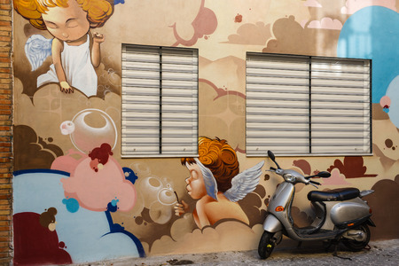 scooter parked in front of wall with graffitiのeditorial素材