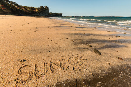 sun with smiley written in sand on beach in New Zealandの写真素材